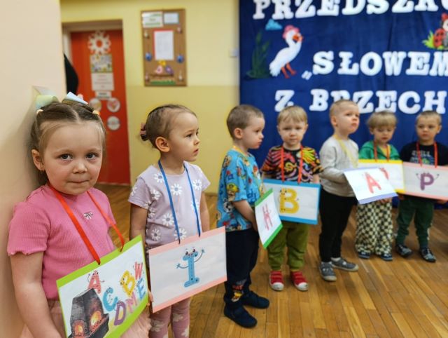 dzieci stoja z literkami