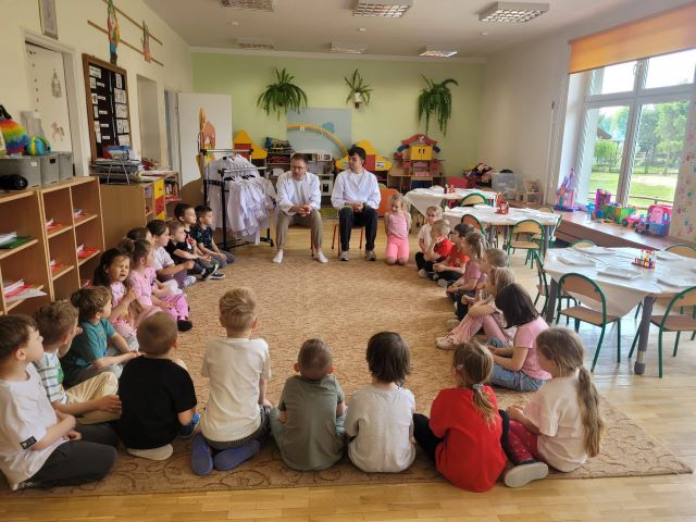dzieci siedza na dywanie sluchaja co beda robic