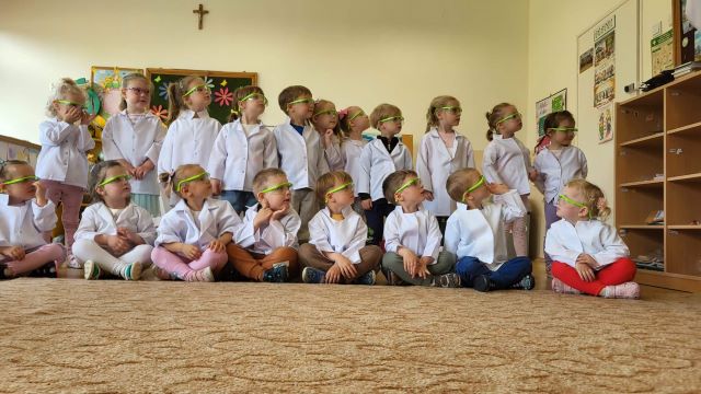 przedszkolaki stoja w fartuchach i goglach